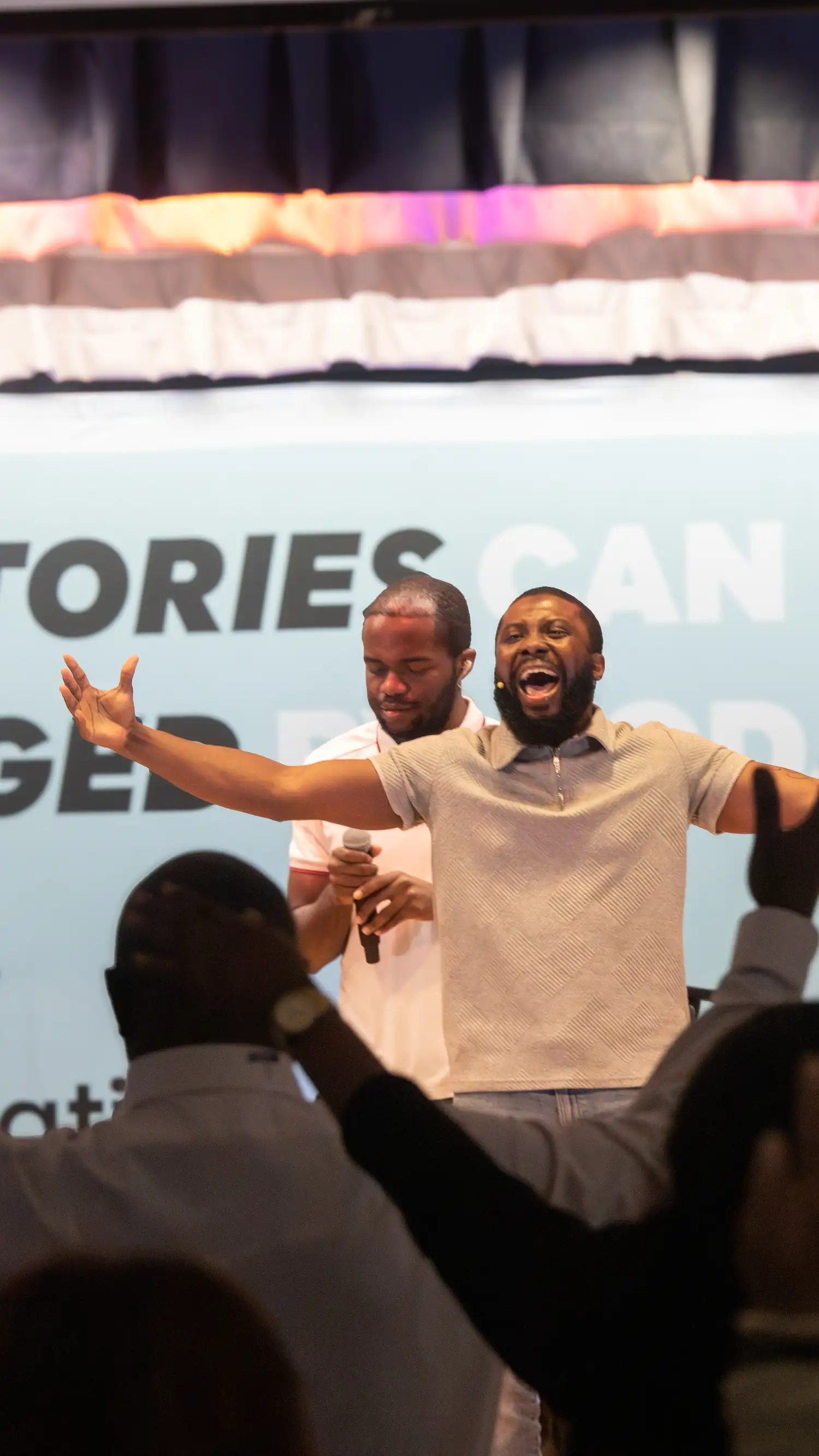 Worship leader singing with arms outstretched as the congregation raises their hands at Restoration Church in Laurel, Maryland