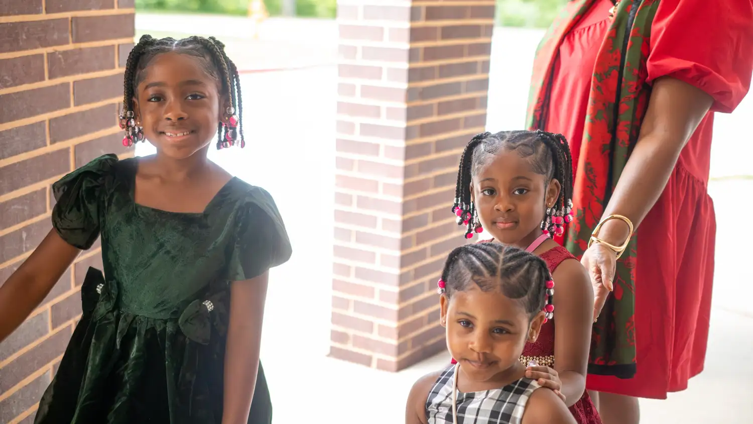 Three young girls in dresses smiling at the entrance of Restoration Church in Laurel, Maryland