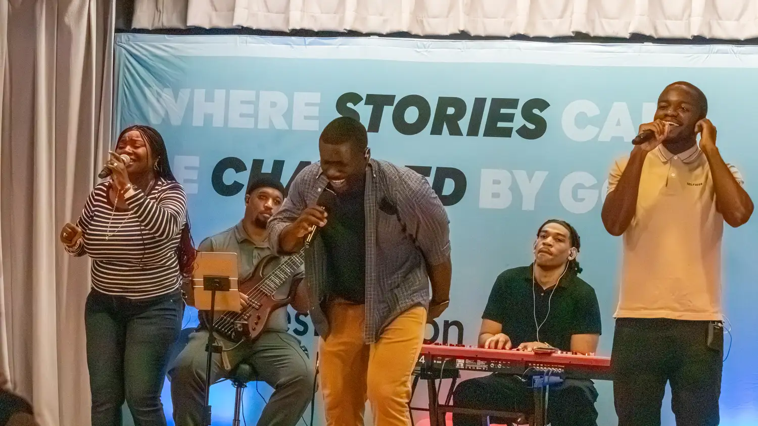 Worship team singing and playing bass and keys on stage at Restoration Church in Laurel, Maryland