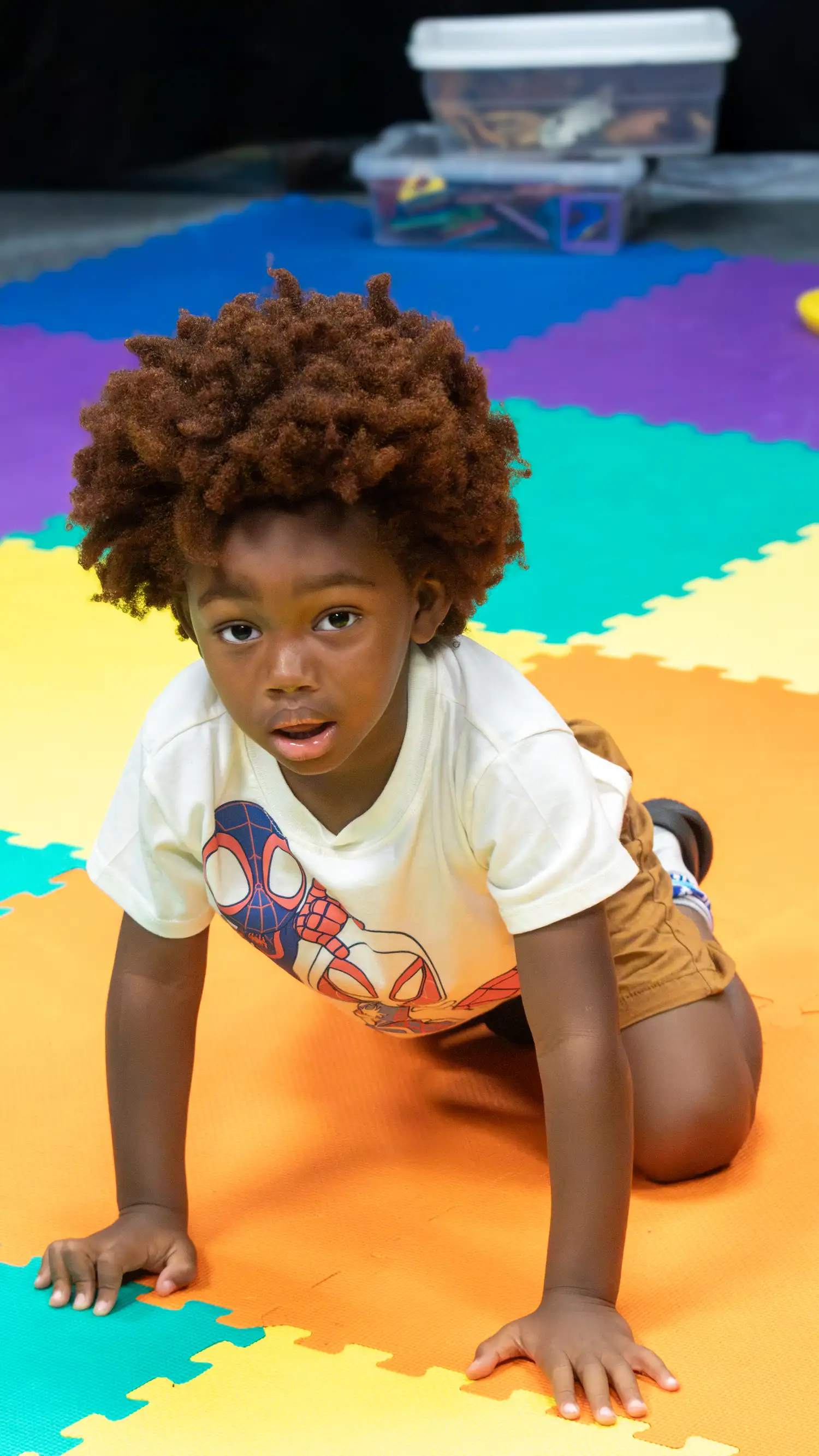 Young boy crawling across colorful foam mats in the kids area at Restoration Church in Laurel, Maryland