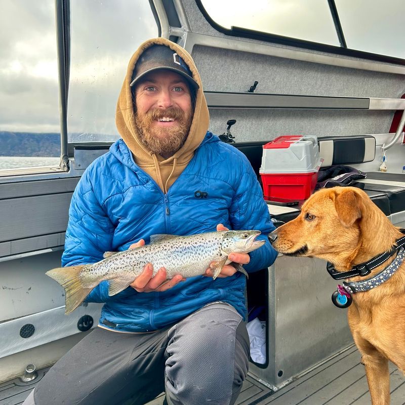 Guest with a catch on Lake Wānaka, Nala looking on