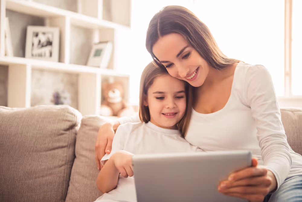 Kid engaging in reading activity in tablet with parent.