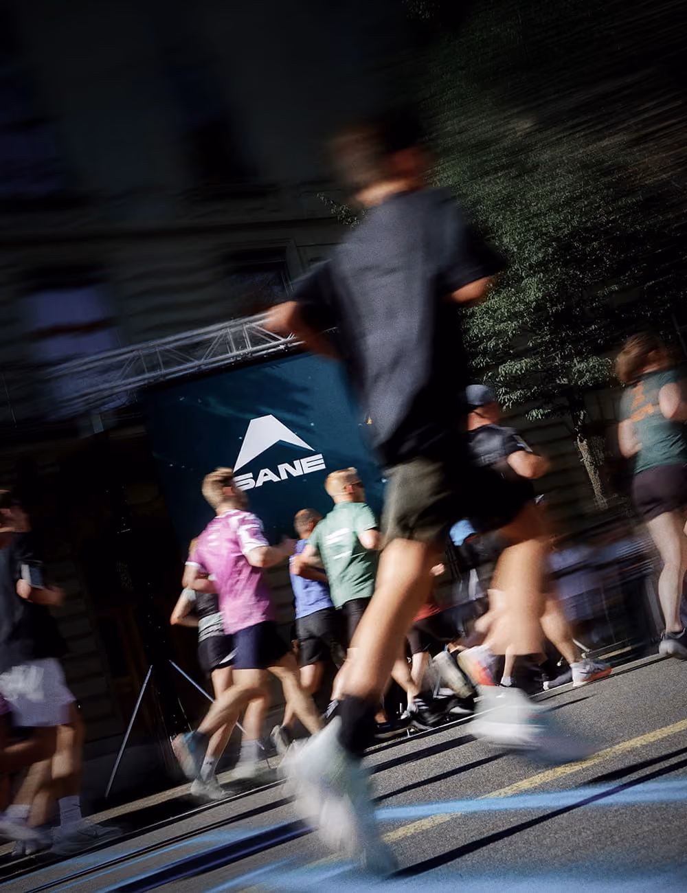 Verschwommene Aufnahme von Läufern bei einem Straßenlauf vor einer SINN-Bande.