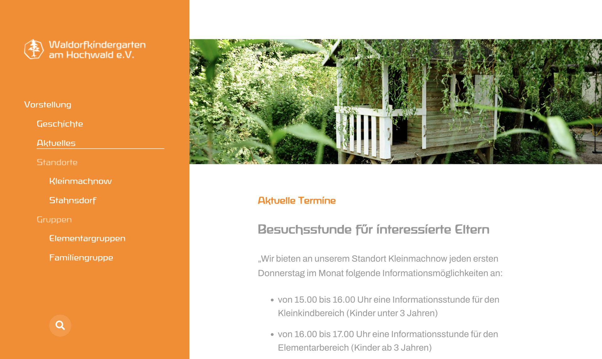 Holzspielhaus auf Stelzen umgeben von grünen Bäumen und Pflanzen im Waldkindergarten.