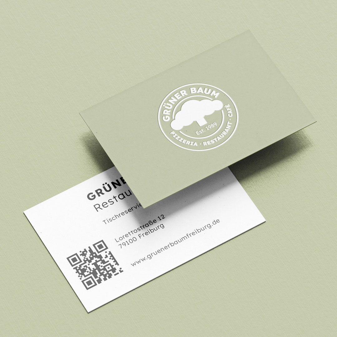 Zwei Visitenkarten des Restaurants Grüner Baum, eine grün mit weißem Baum-Logo, die andere weiß mit Adresse und QR-Code.