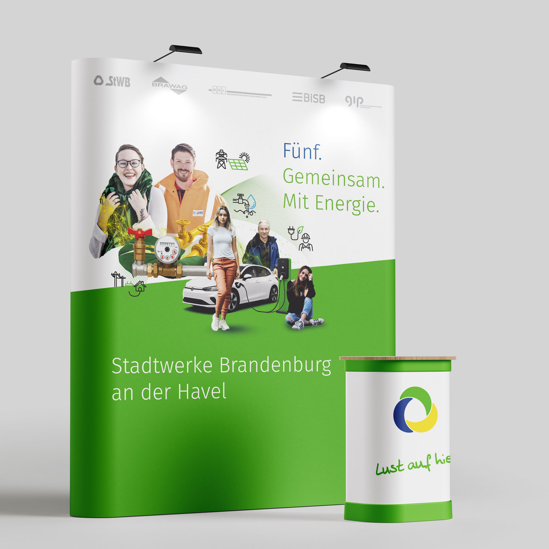 Messestand der Stadtwerke Brandenburg mit Bildern von Mitarbeitern, einem Elektroauto und Energieicons sowie dem Text ‚Fünf. Gemeinsam. Mit Energie.‘.