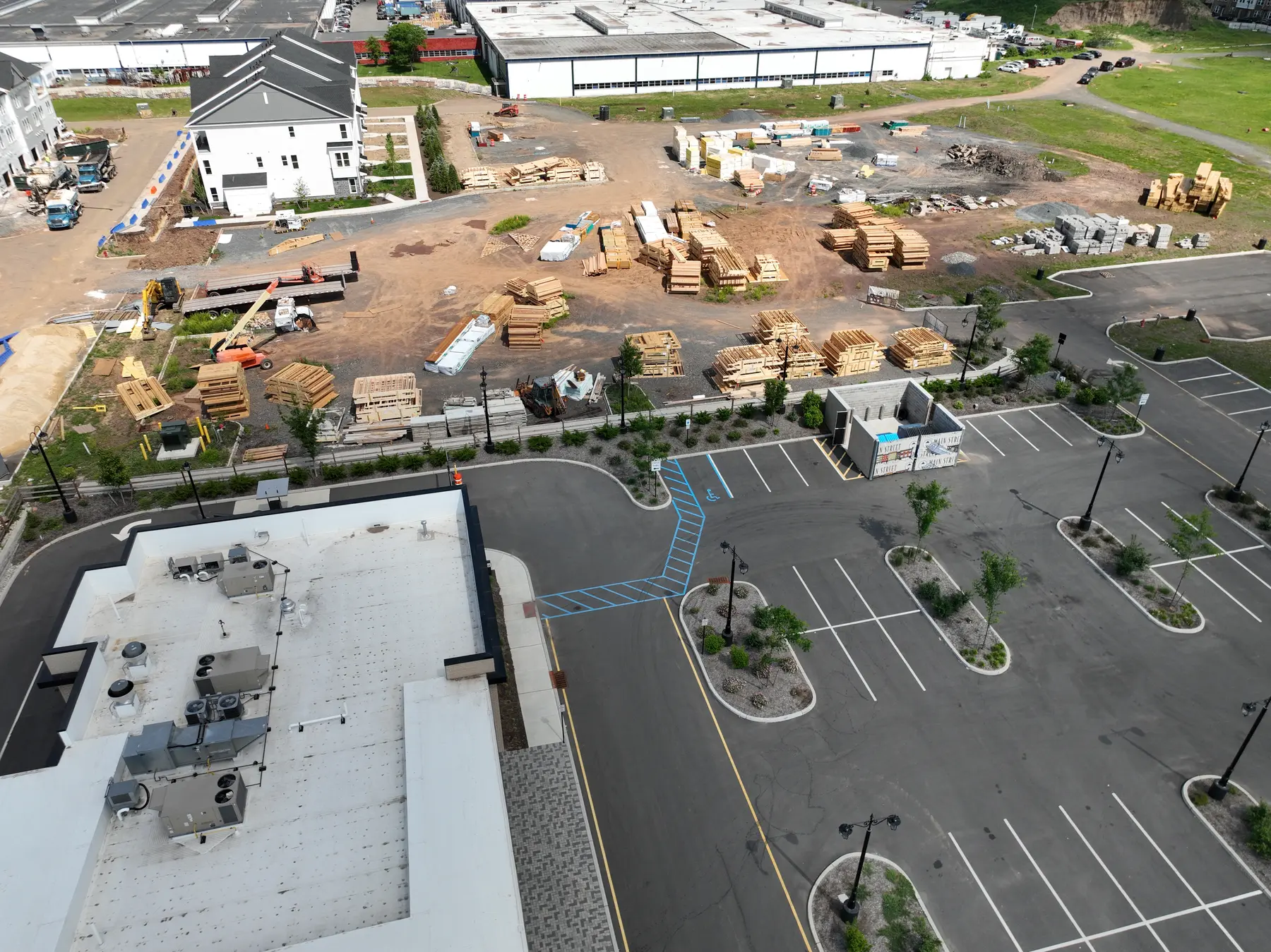 Aerial overview of an active construction site showing buildings, work areas, access roads, and staging zones