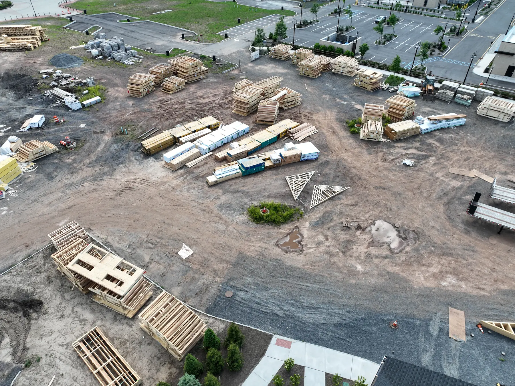 Aerial construction documentation showing staged lumber, building materials, equipment, and site logistics