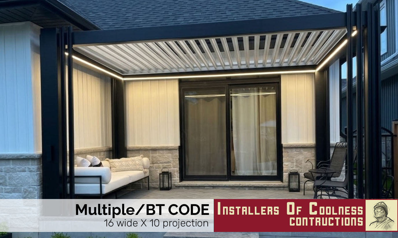 White house exterior with large window covered by a dark metal awning and garden with flowers below.