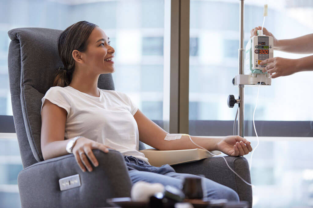 Woman smiling while receiving IV infusion therapy