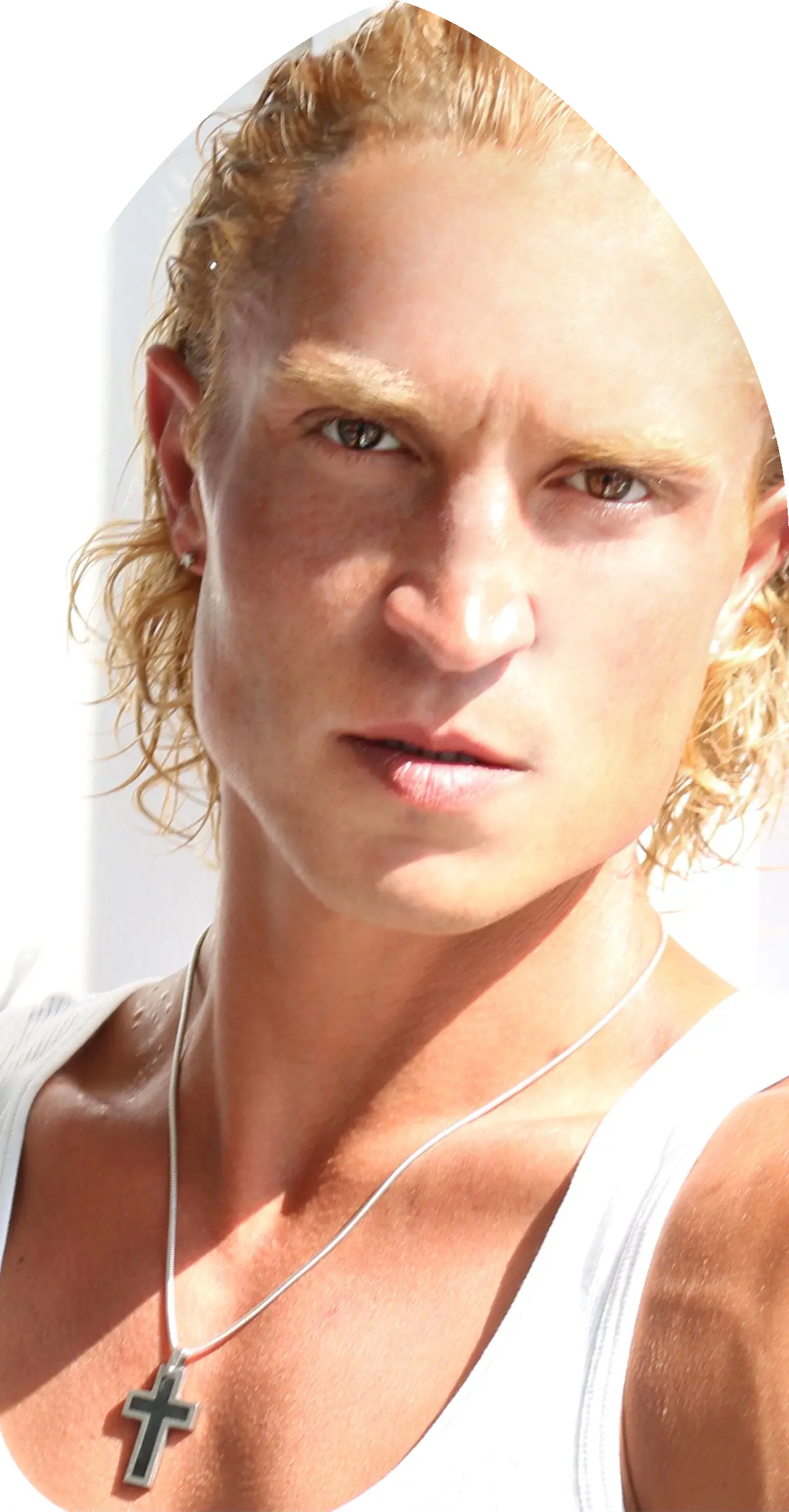 Portrait en gros plan d'un homme blond aux cheveux bouclés, portant un débardeur blanc et un collier avec une croix.
