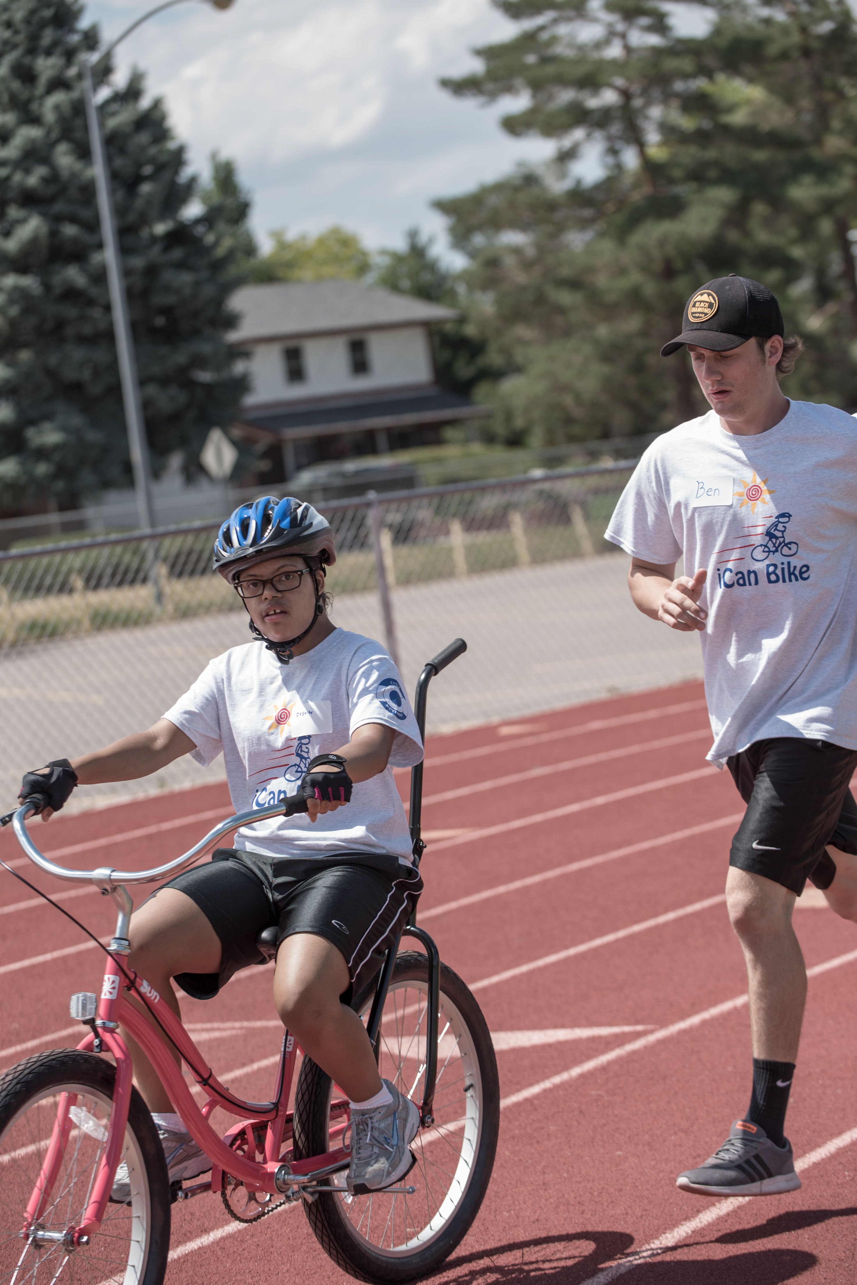 iCan Bike instructor running alongside a child with a disability learning to ride a bike at Cycle Movement's adaptive cycling program in Colorado