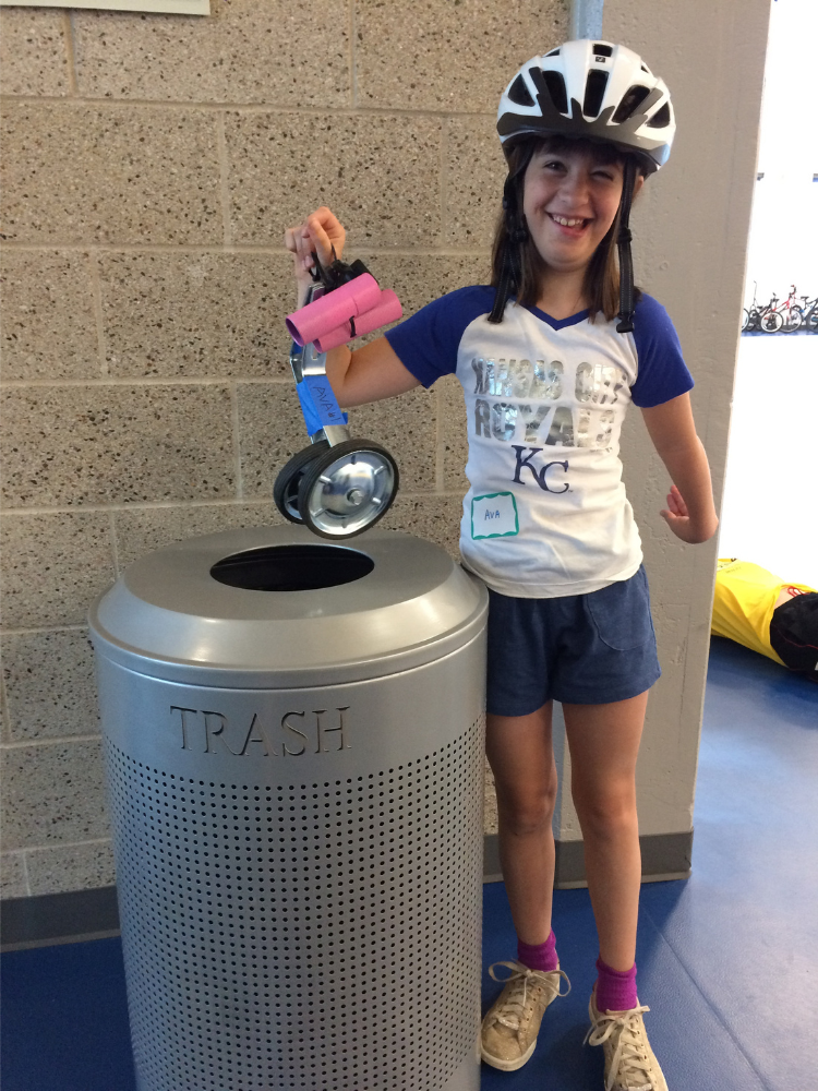 Young girl with a disability wearing a bicycle helmet and celebrating after learning to ride a bike at Cycle Movement's adaptive cycling program in Colorado