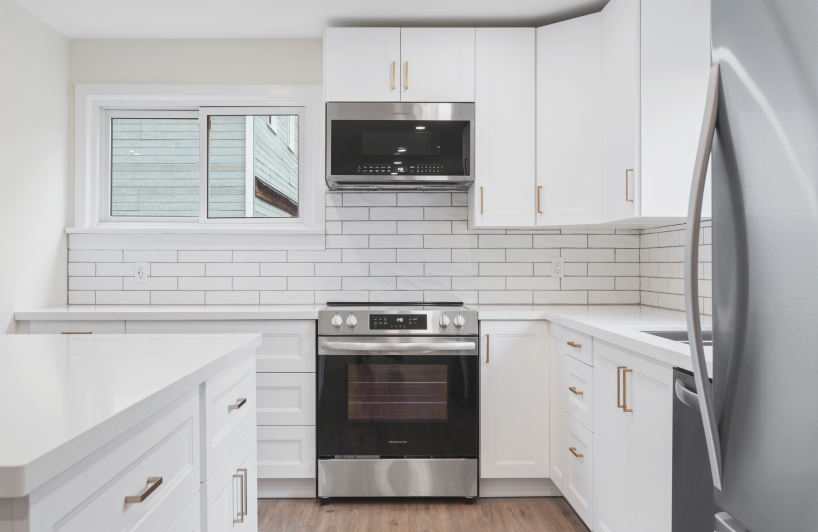 Aerial view of a snowy landscape with a frozen lake featuring small islands and tire tracks, surrounded by snow-covered trees and houses.