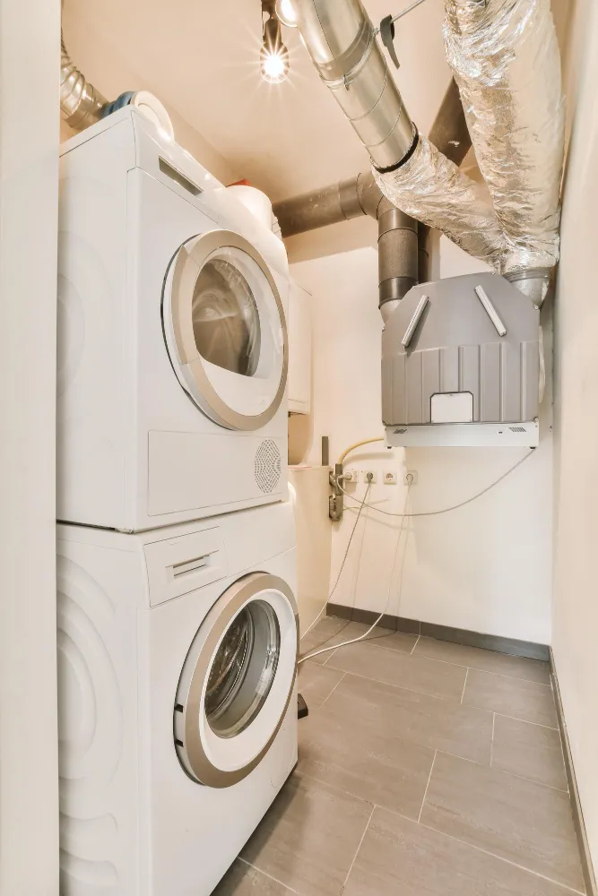 Stacked washer and dryer with ventilation system in laundry room