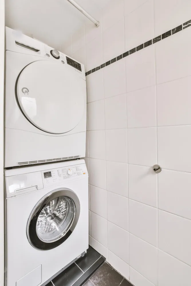 Stacked washer and dryer installed in tiled laundry space