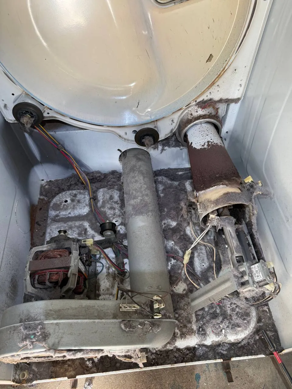 Dryer interior with heavy lint buildup and exposed components