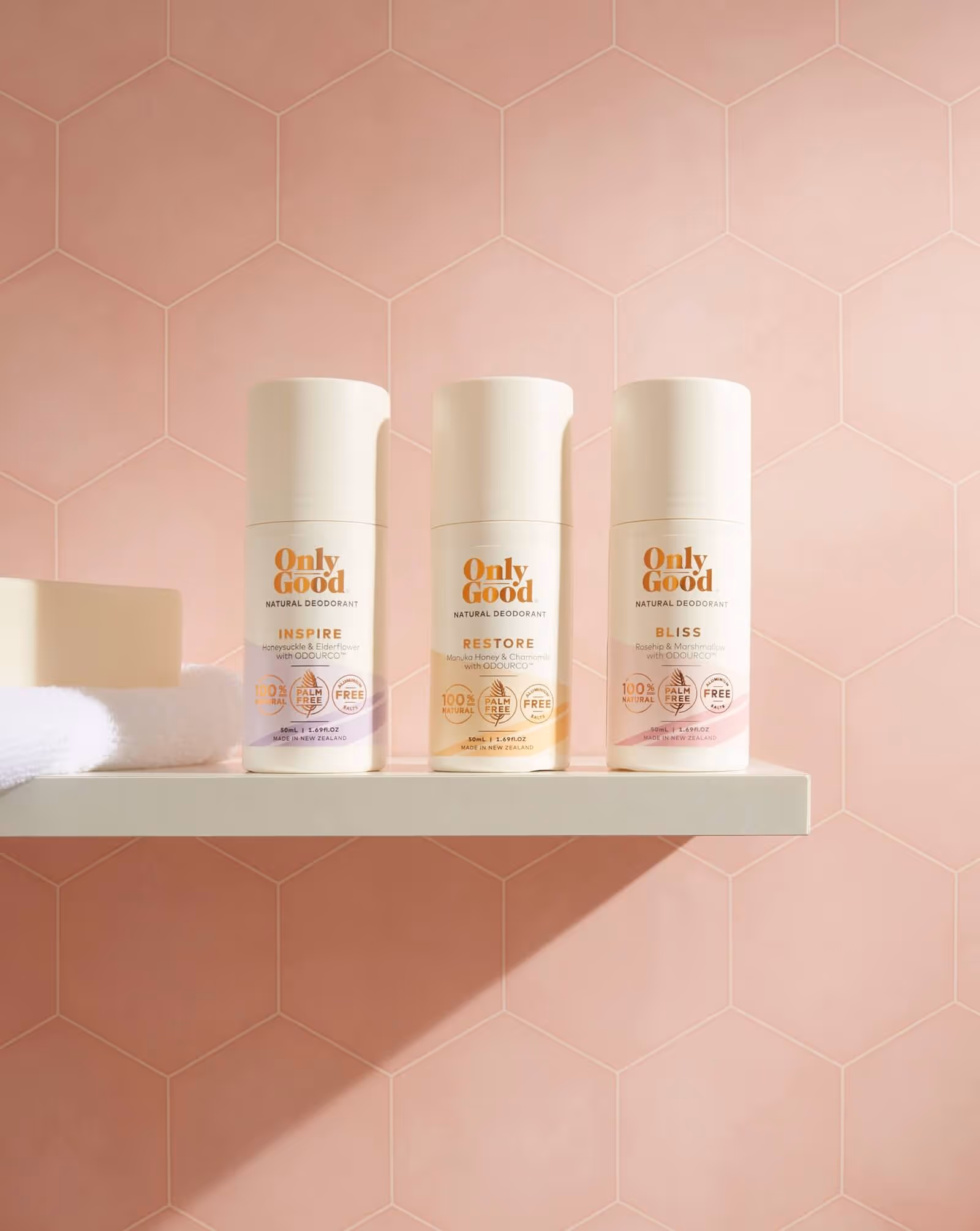 Professional product photography of Only Good natural skincare bottles arranged on a shelf against a pink hexagonal tile background