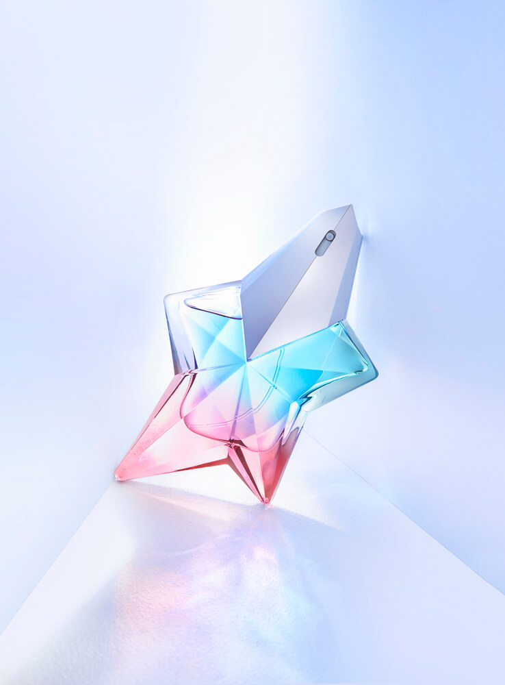 A perfume bottle in a star shape with reflections and colours