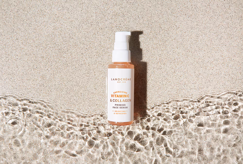 Face serum shot from above showcasing sunlight sand and a light wave hitting the bottom of the serum
