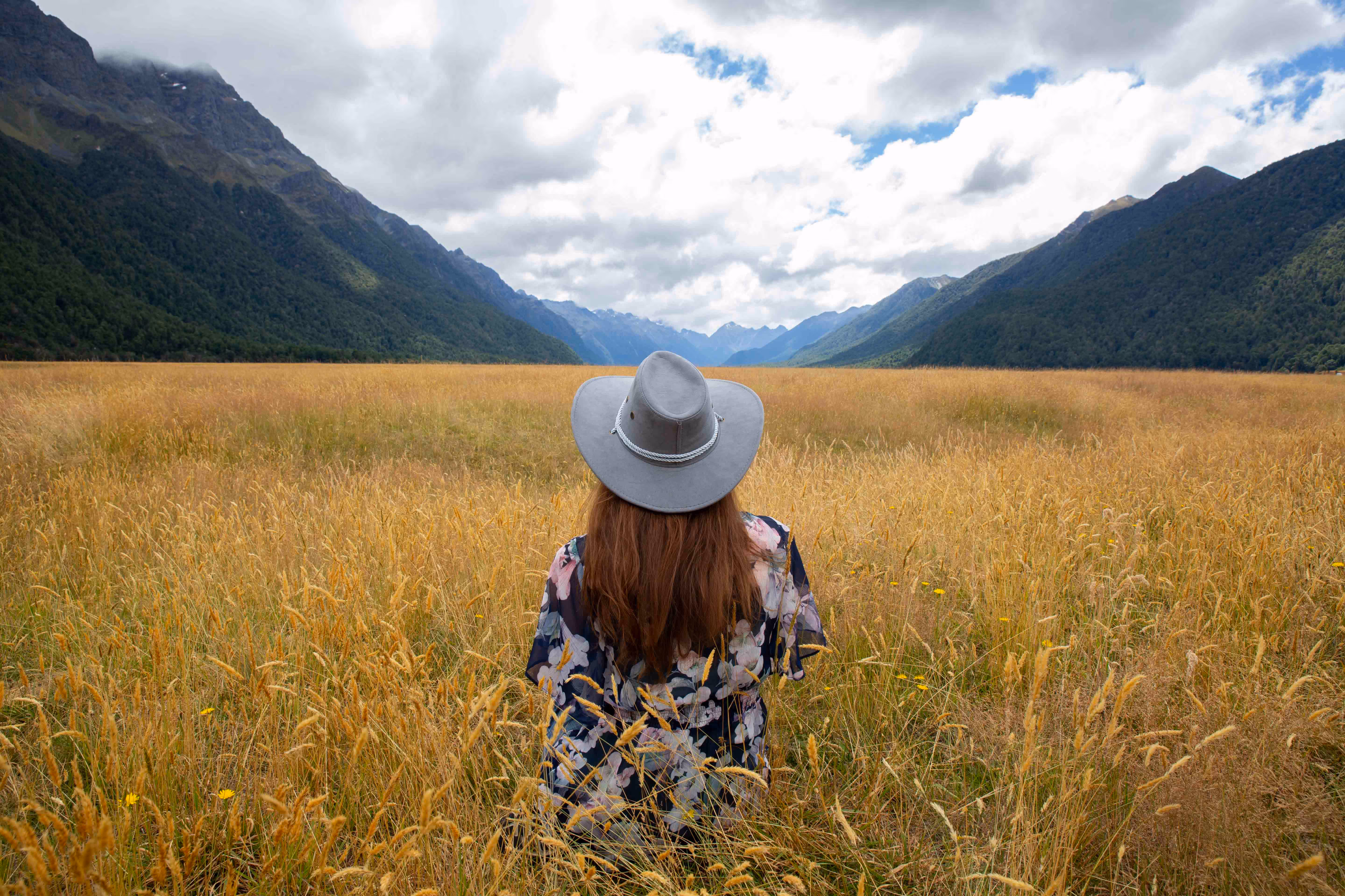 Amanda in a field of long grass overlooking Milford Sound