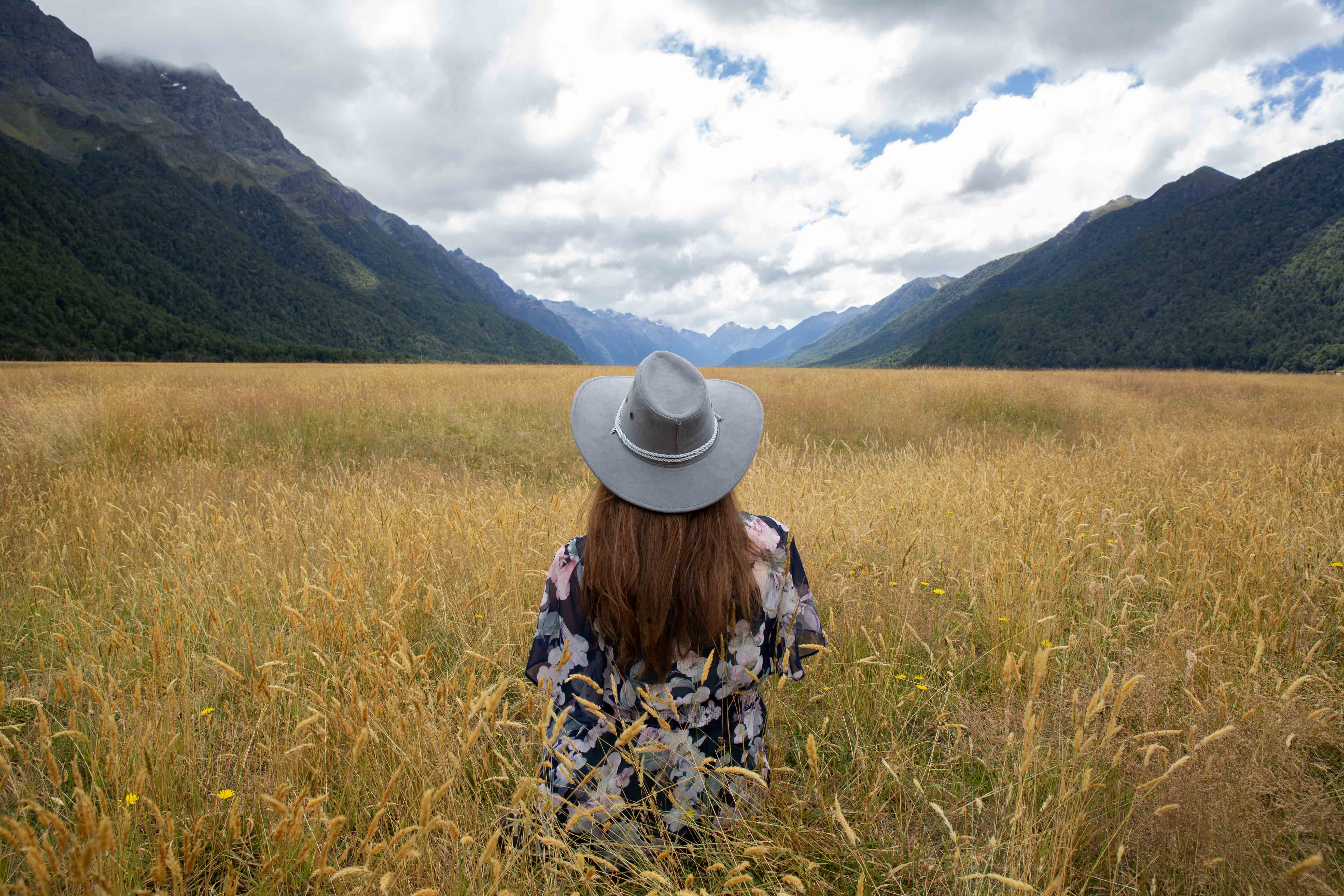 Amanda in a field of long grass overlooking Milford Sound