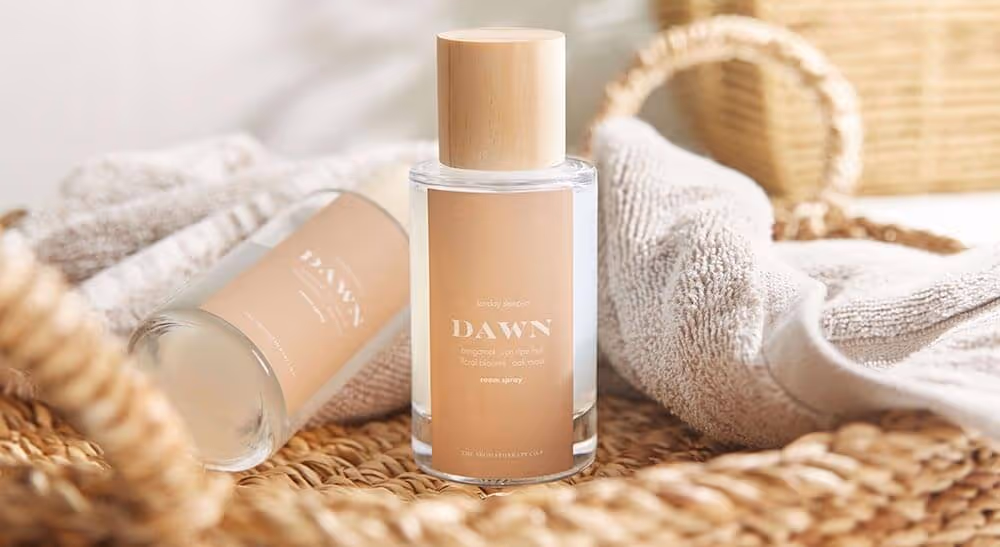 DAWN fragrance and body spray bottles styled with wicker basket and towels — lifestyle product photography Auckland