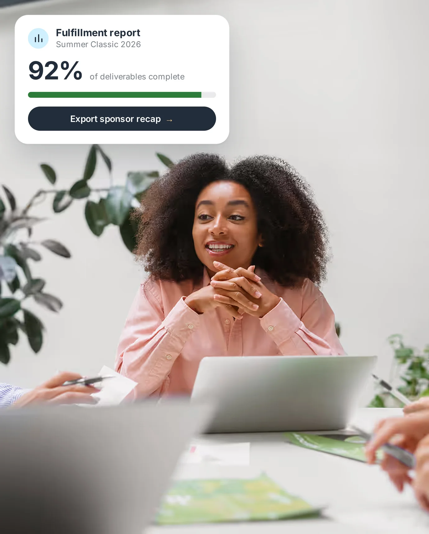 Smiling event lead in a meeting, with a PartnerHQ fulfillment report showing 92% of deliverables complete.