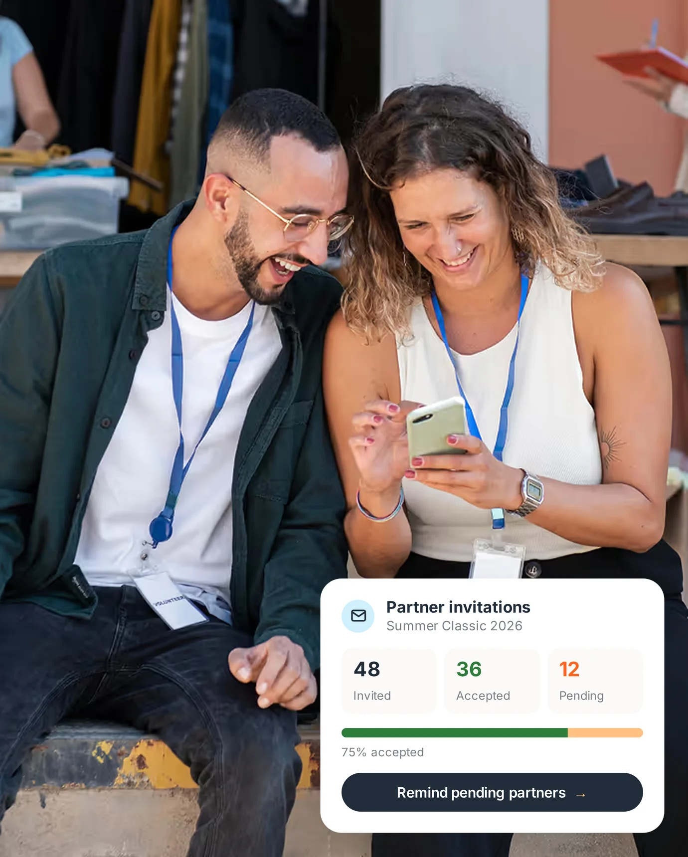 Two event team members smiling at a phone, with a PartnerHQ card showing partner invitations: 36 of 48 accepted, 12 pending.