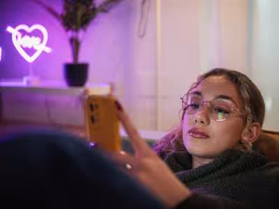 Close up of a girl on her phone, scrolling, in an LED light room.