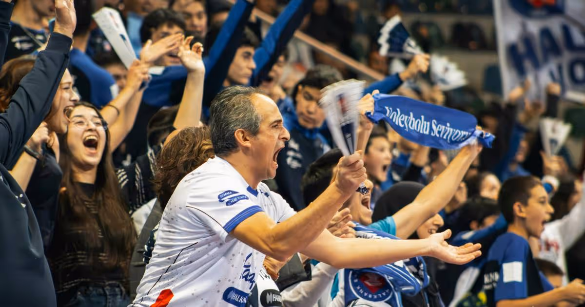 Fans celebrating at a football match in the crowd.