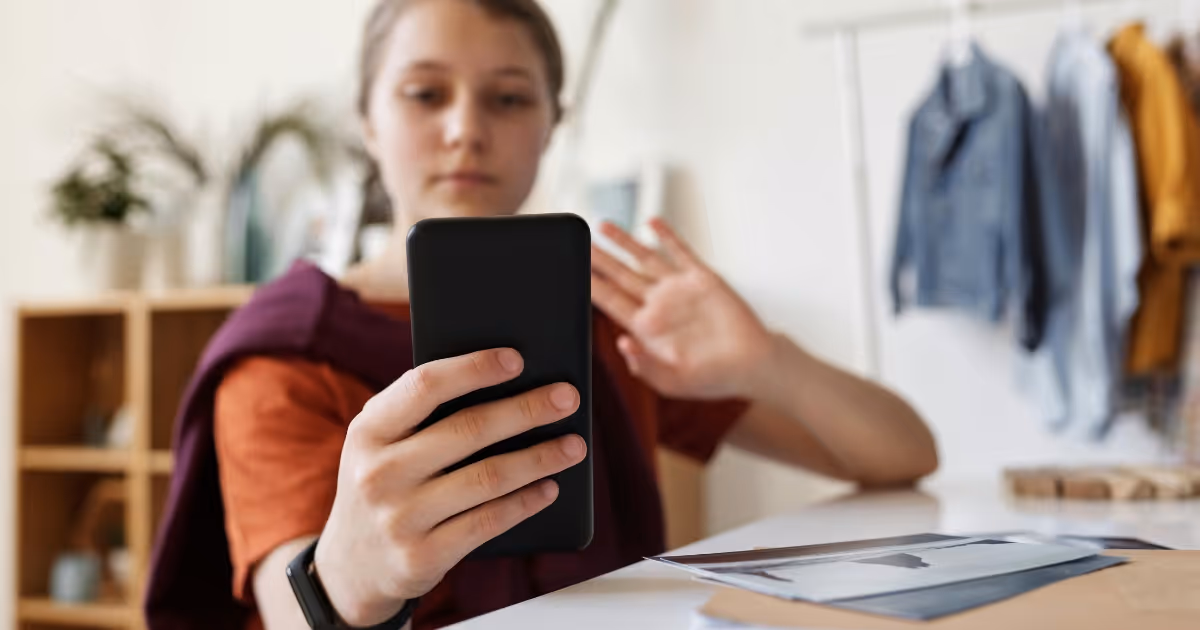 Woman waving to phone camera.