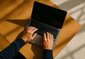 Hands at a laptop, view from above.