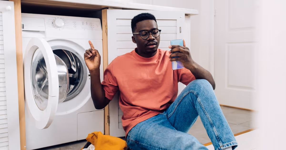 Man using phone while at the washing machine.