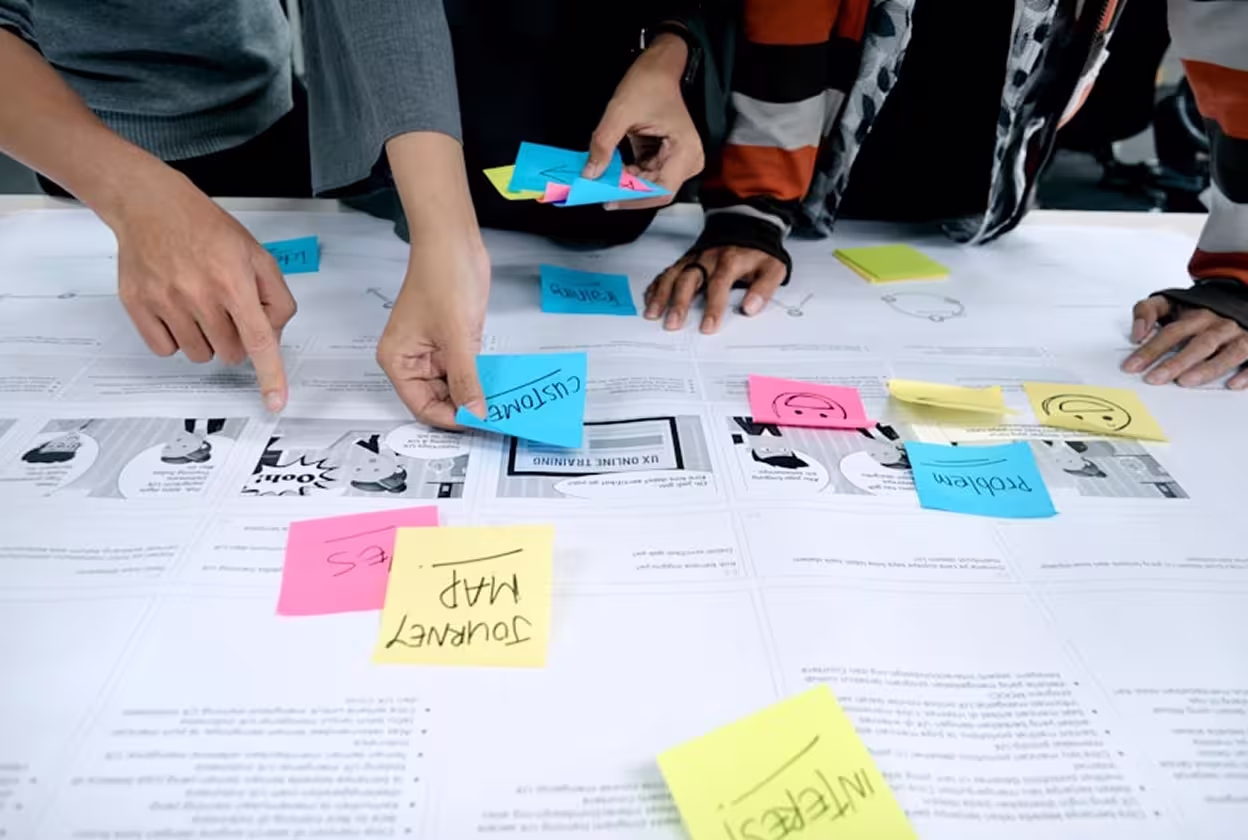Close up of hands arranging post it notes on a table.