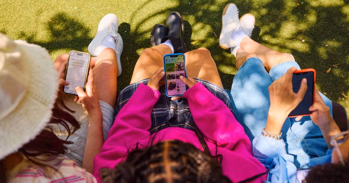 Friends scrolling on their phone in a park.
