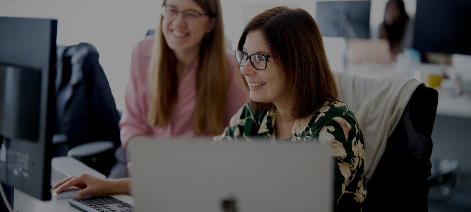Two Indeemo employees talking at their desks.