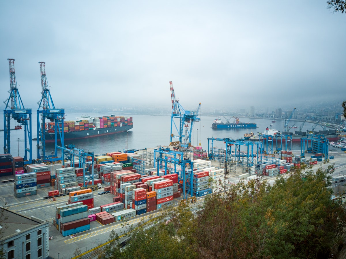 A container terminal on a misty morning, blue quay cranes and a container ship berthed alongside