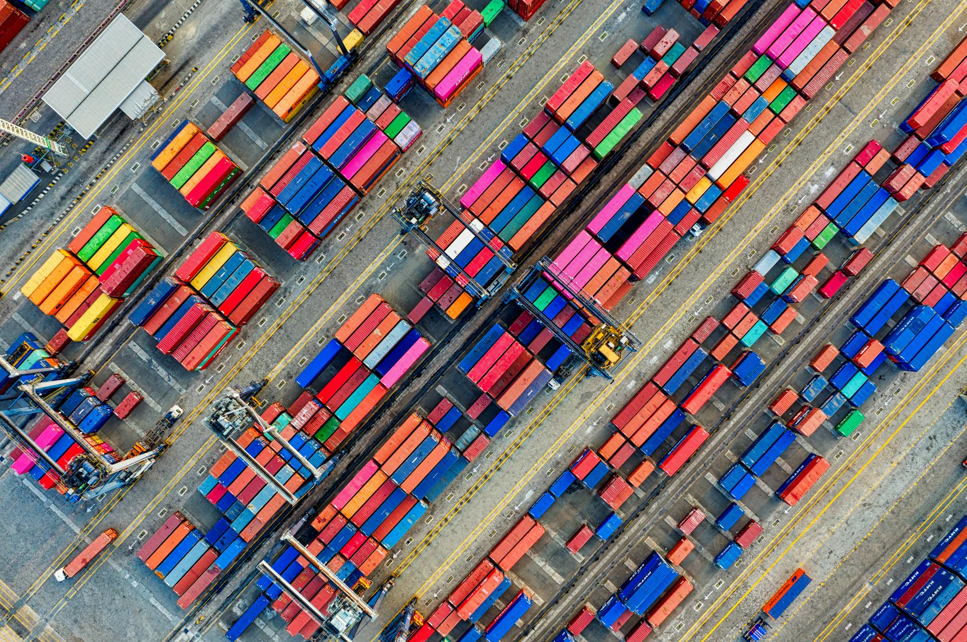 Straight down aerial view of a container yard, coloured containers in rows between yellow lane markings
