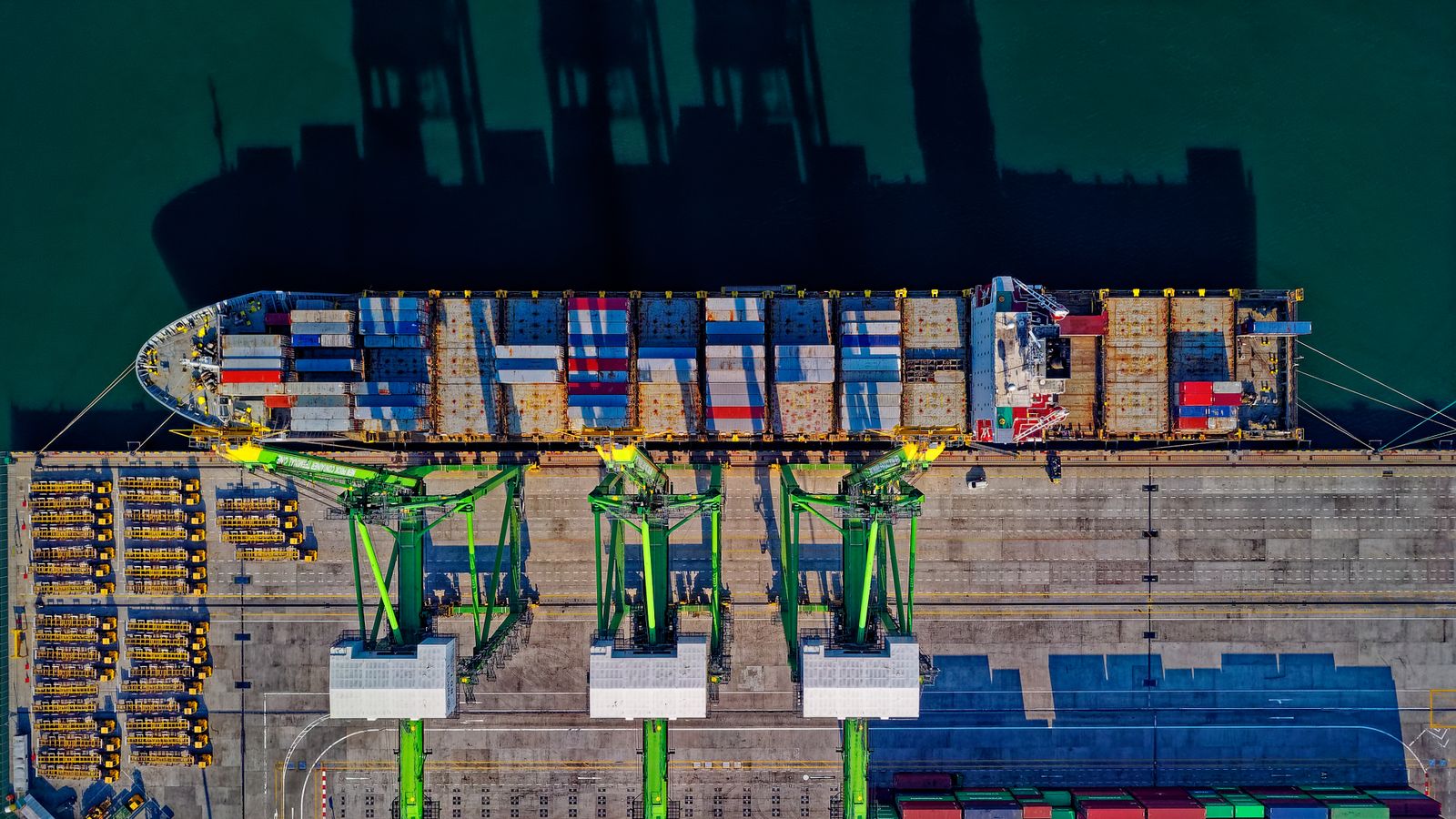 Overhead view of a container ship being worked by three quay cranes at a terminal berth