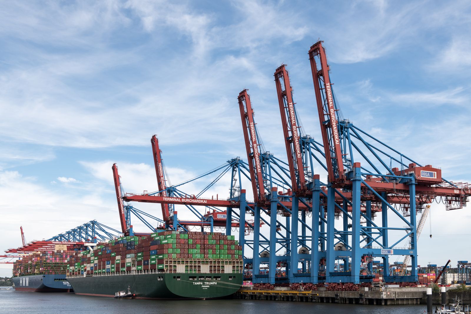 Two laden container ships moored side by side at a container terminal, one flying the flag of Panama.