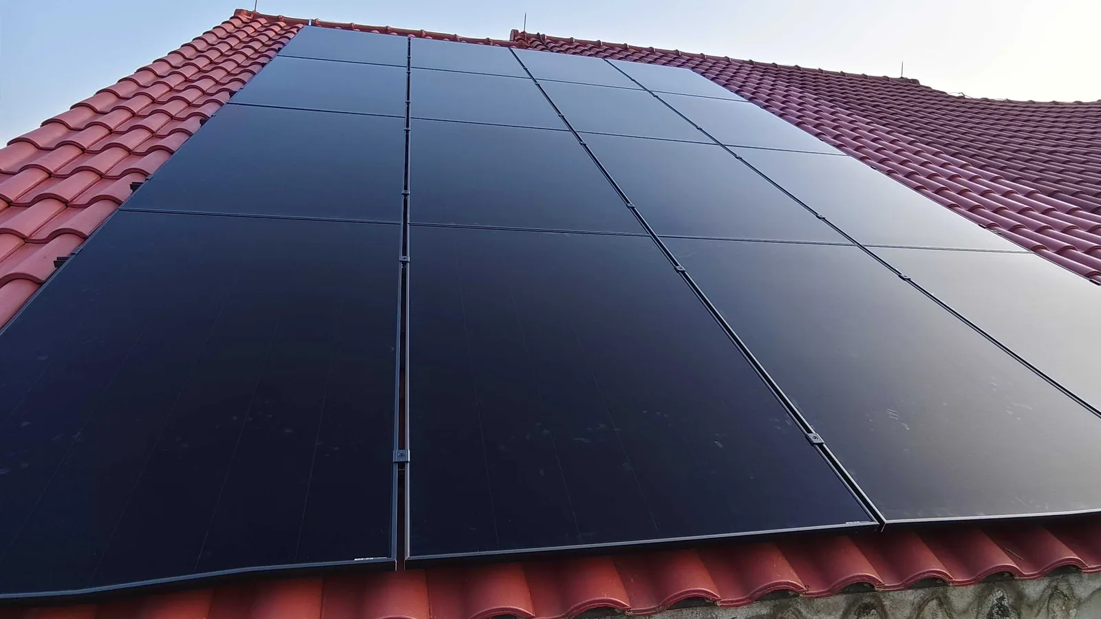Low-profile black solar panels mounted flush on a red clay-tile pitched roof in Singapore, a layout suited to conserved and heritage homes.