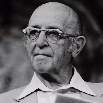 Elderly bald man wearing glasses and a collared shirt looking slightly to the side.