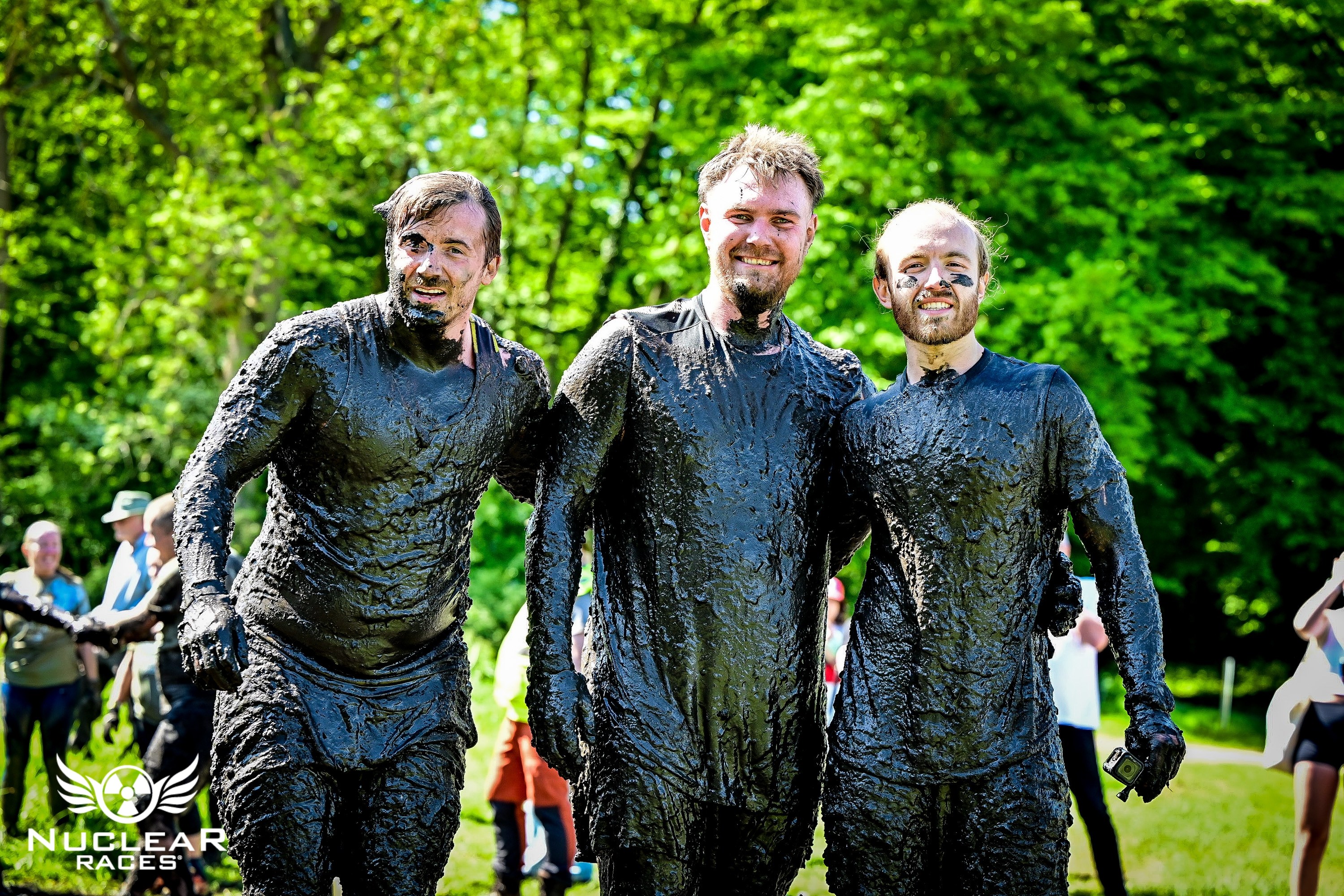Three athletes covered in mud after finishing a Nuclear Races obstacle course