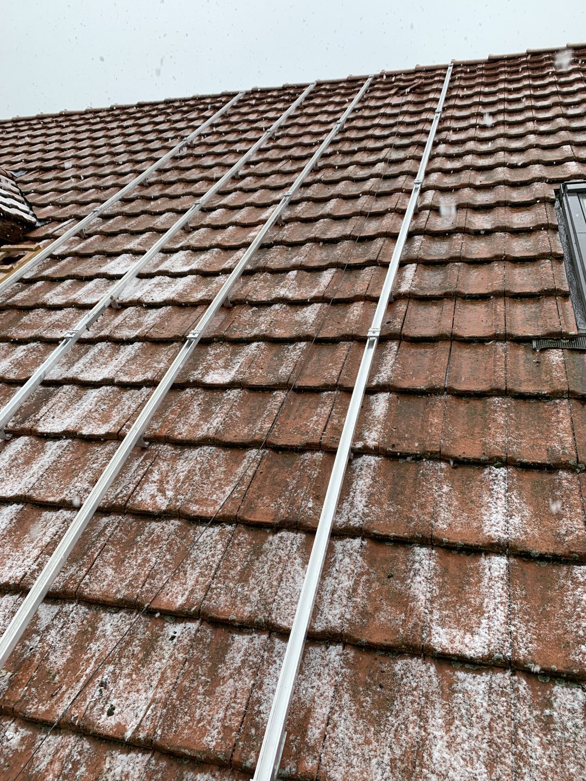 Montageschienen auf dem alten Ziegeldach in Jens bei Schneefall