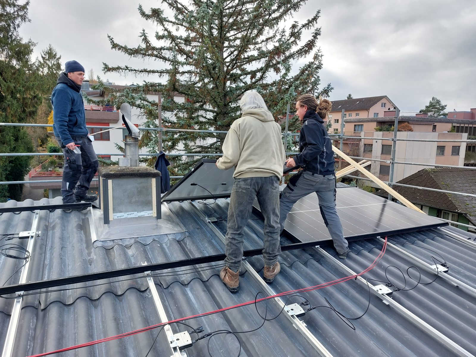 Solarmaa-Team und Bauherr montieren gemeinsam Module auf dem Welleternitdach in Port