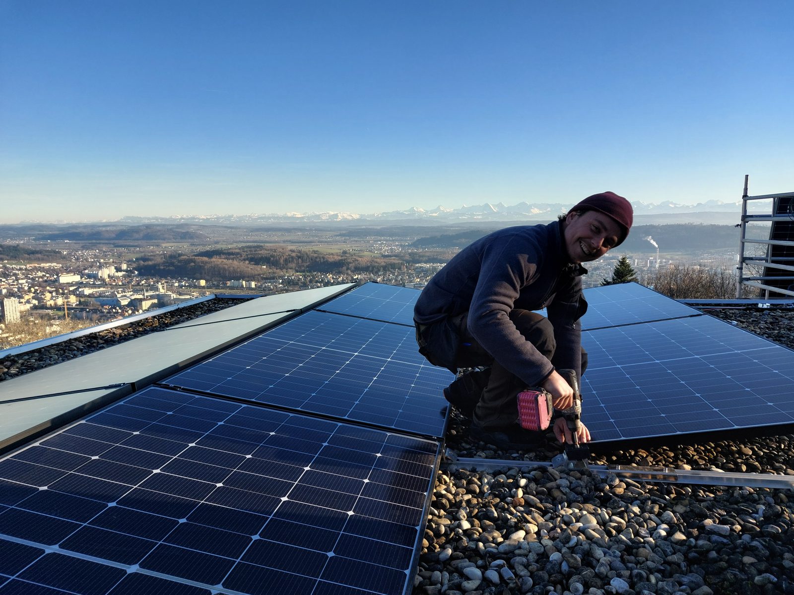 Solarmaa-Monteur montiert Module auf einem Dach in Évilard mit Blick über den Bielersee