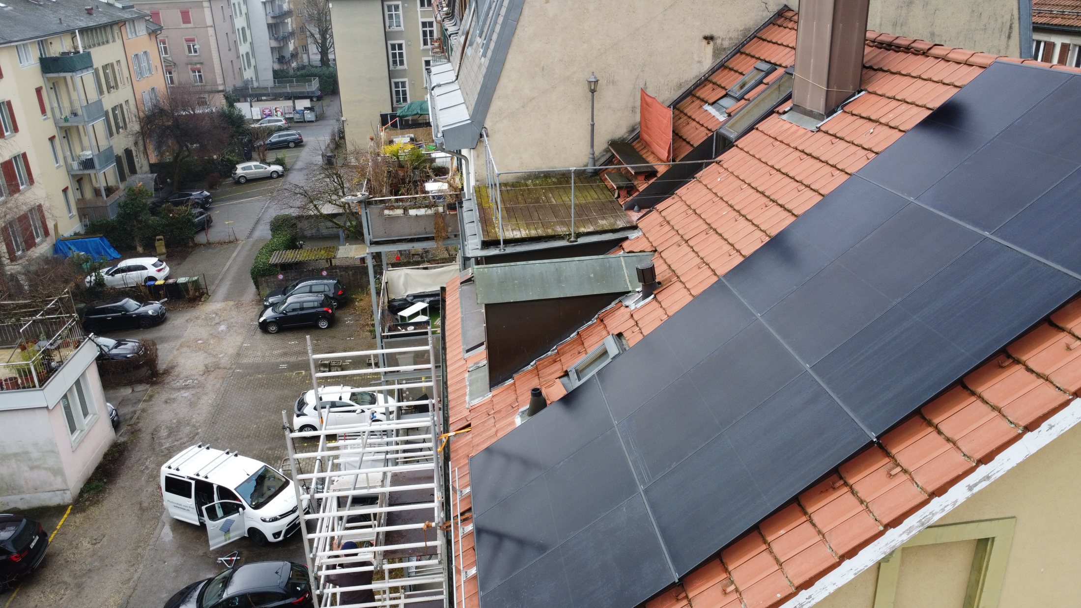Vollschwarze Aiko-Solaranlage auf dem Ziegeldach eines Wohnhauses von 1896 in Biel, Drohnenaufnahme über dem Strassenzug