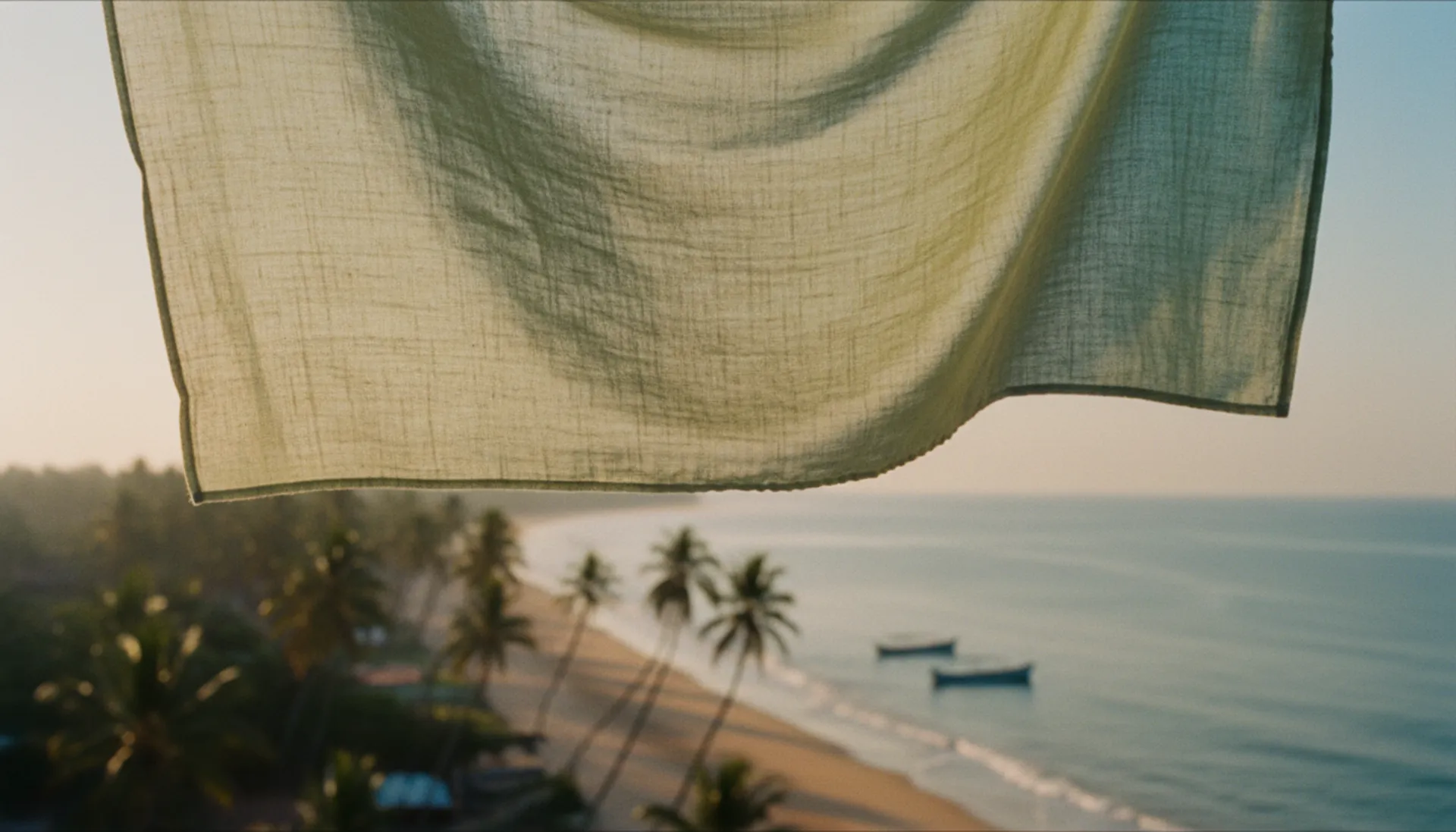 Light cotton fabric billowing in a sea breeze with the Kerala coastline softly blurred in the background