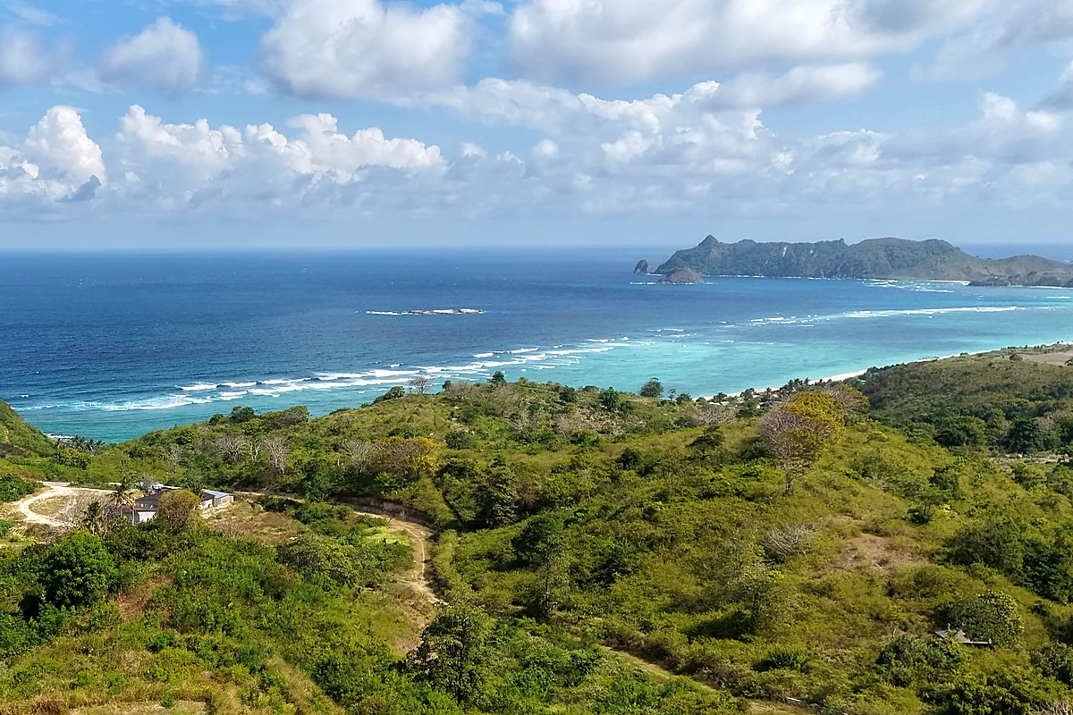 Aerial view of an undeveloped green headland in south Lombok above a turquoise reef